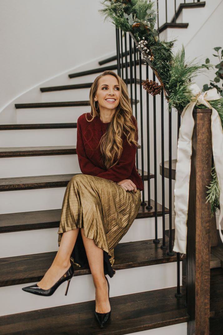 merrick on stairs with gold pleated skirt and burgundy cable knit sweater