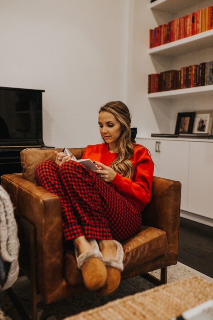 girl in red christmas pajamas sitting on leather chair reading book