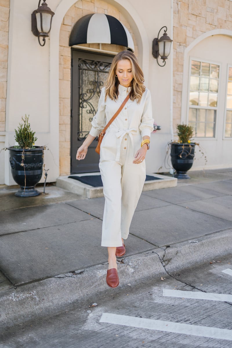 cream jumpsuit with brown flats and crossbodybag